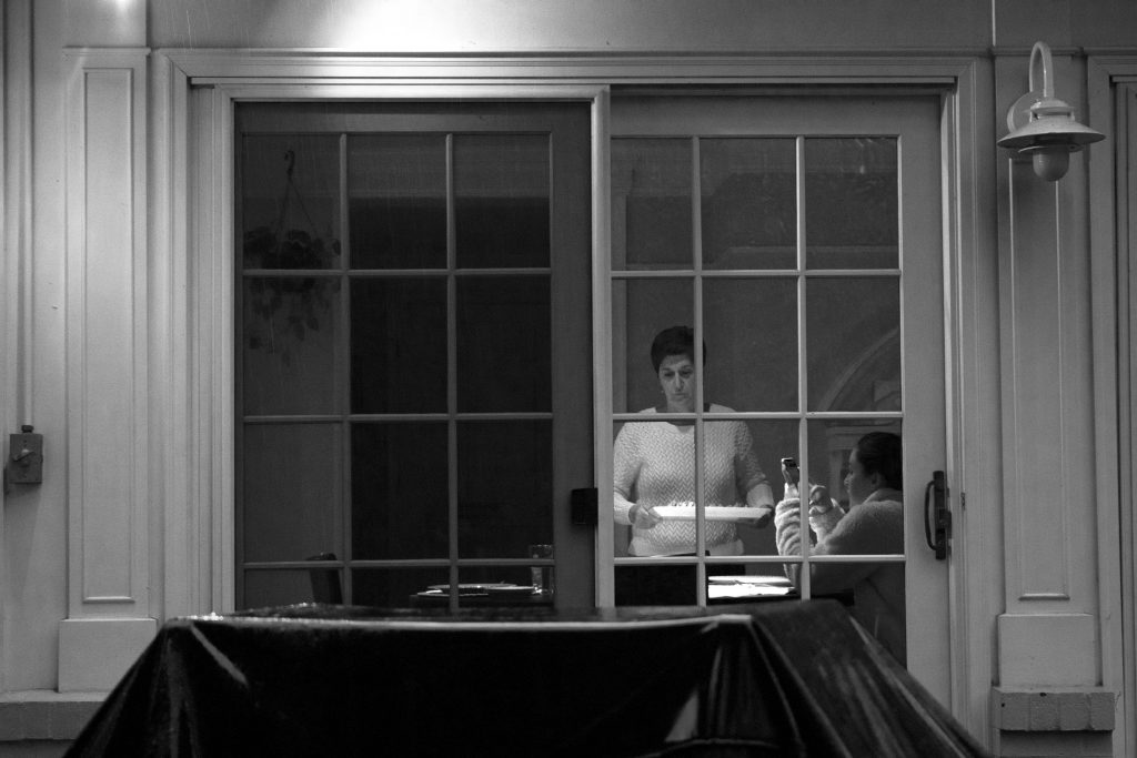 People getting ready for dinner through a window