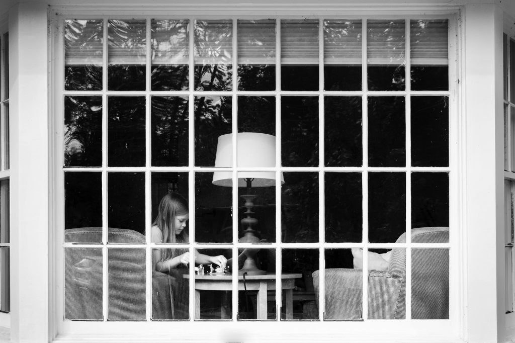 Girl playing with legos through a window