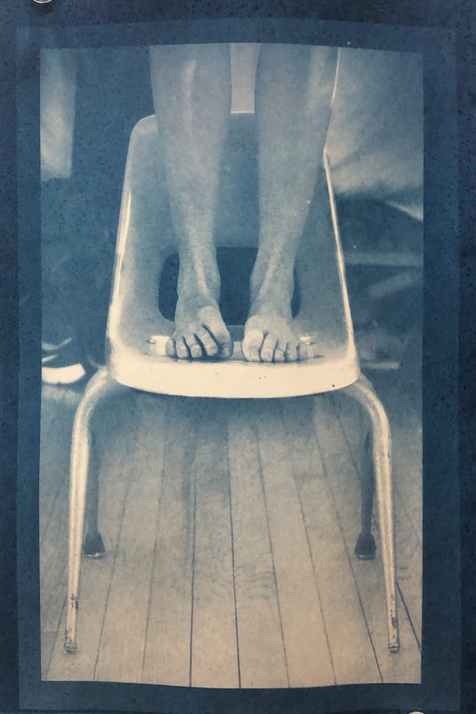 Person's legs standing on a small chair.