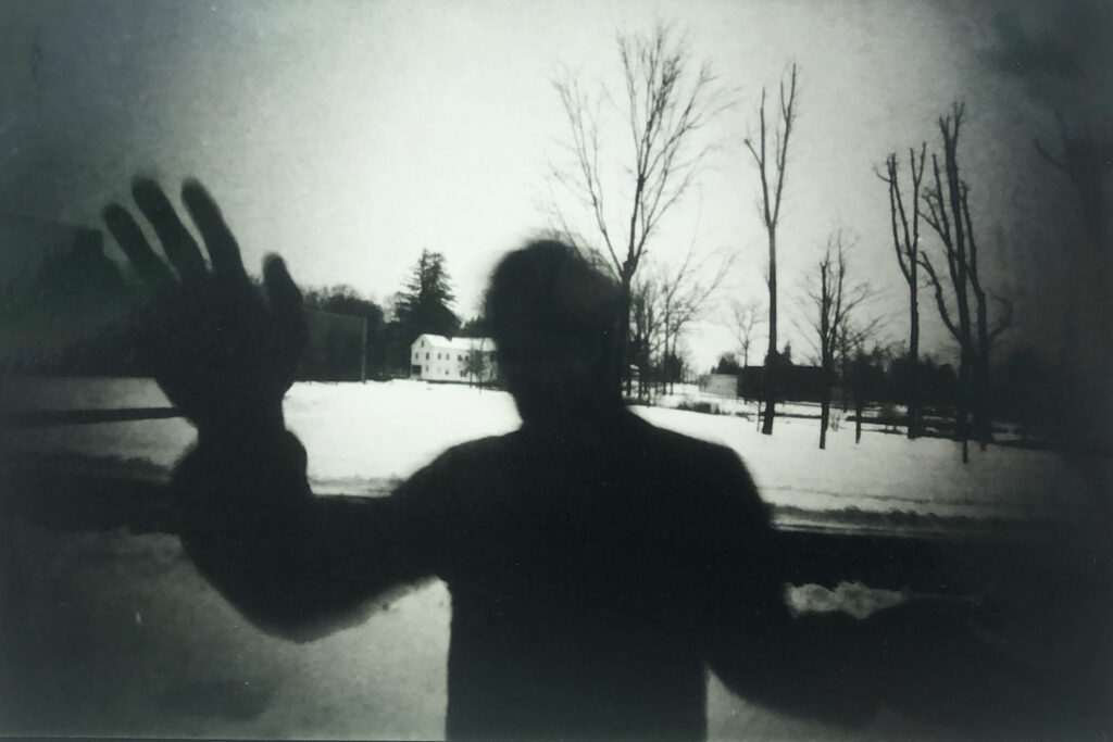 a pinhole image of a silhouette of a man waving at the camera