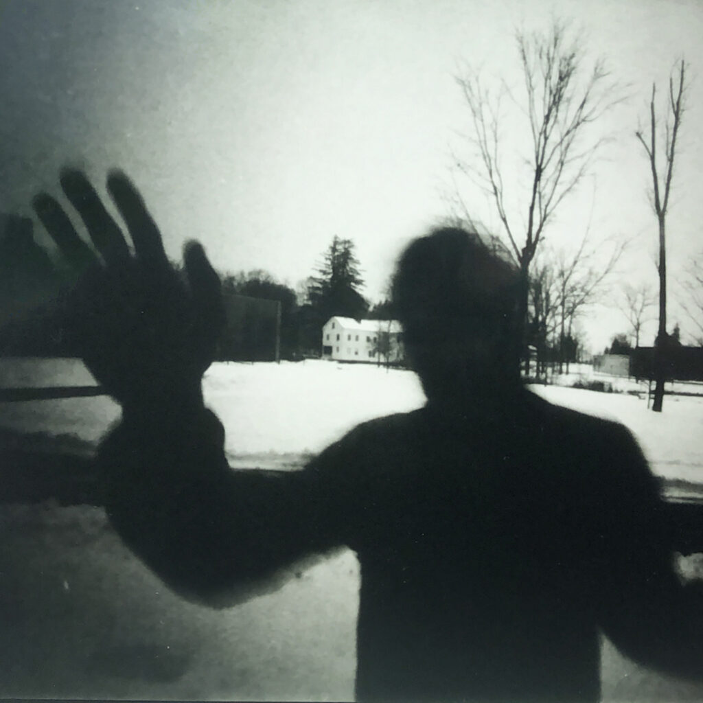 a pinhole image of a silhouette of a man waving at the camera